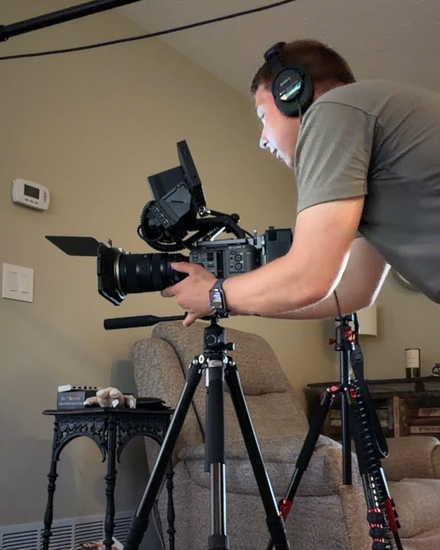 Alex Belser with his camera on a tripod in a living room